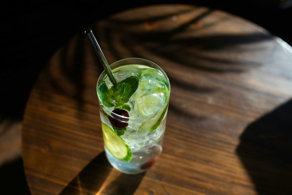 Close-up of a refreshing mojito with mint, lime, and ice in a glass on a wooden table.